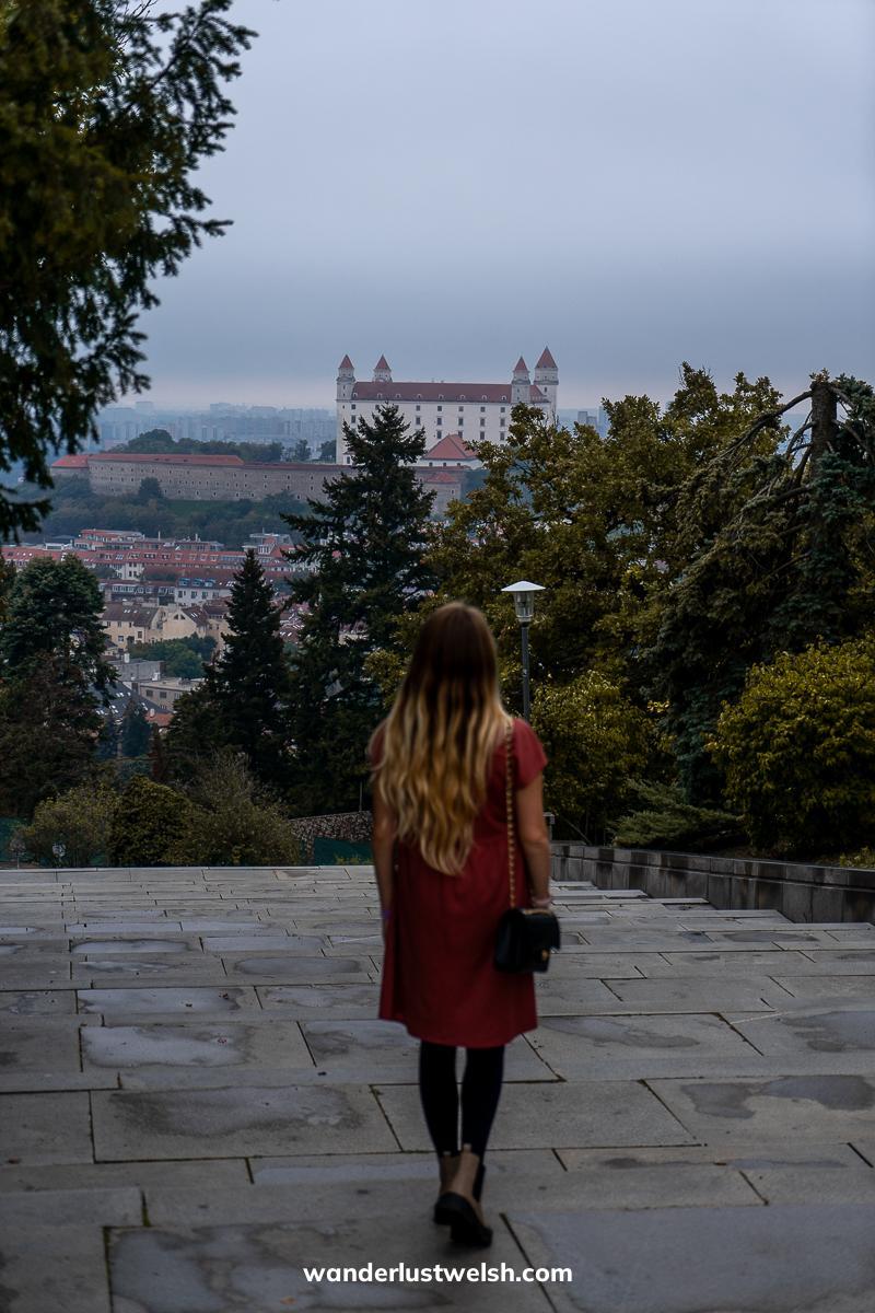 A woman looking out over Bratislava - most notably the castle - from a distance