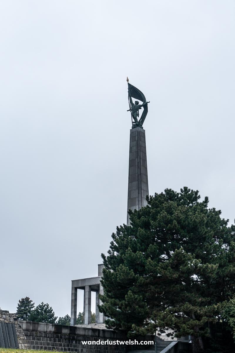 A war memorial with tall obelisk topped with a statue of a soldier raising a flag