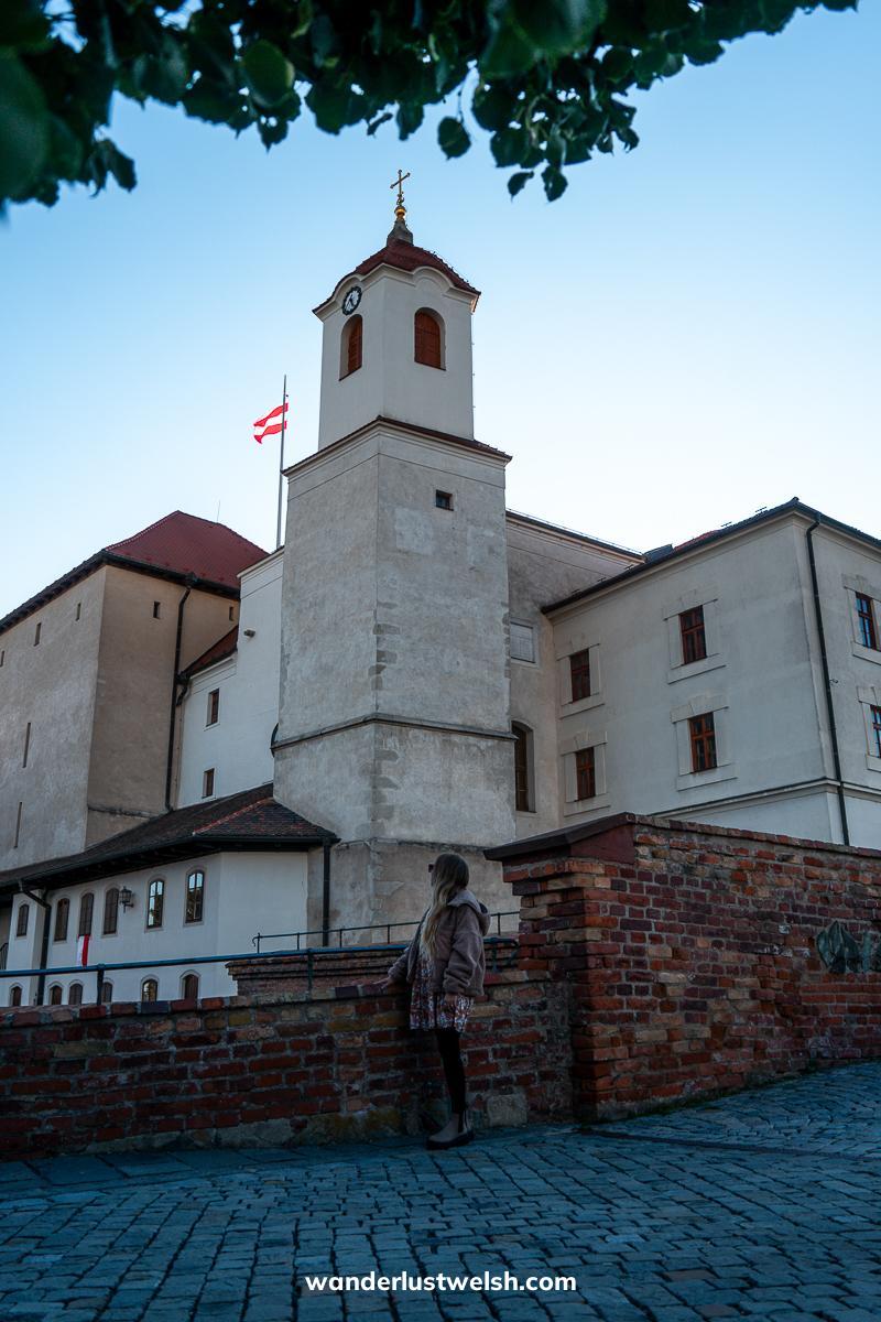 A woman looking at Spilberk Castle in Brno - A white castle with a tower