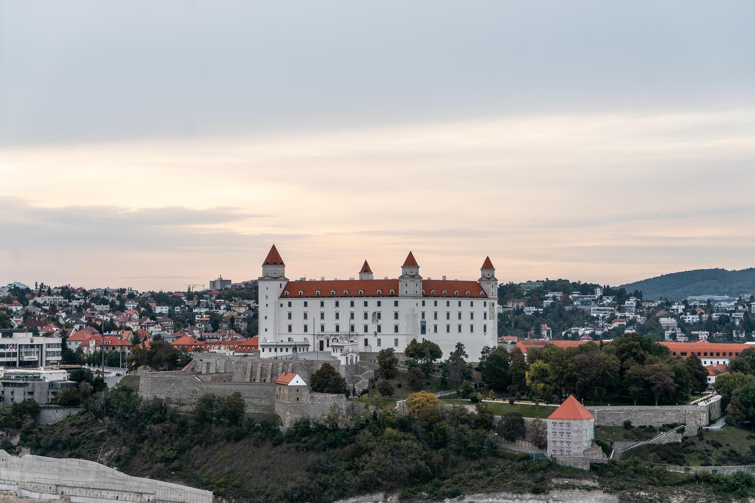 A wide view of Bratislava castle - a white castle with orange roof - and some of the city