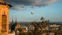 A view of Brno from a high castle viewpoint - A castle tower, double spired cathedral, and a hot air balloon in the sky