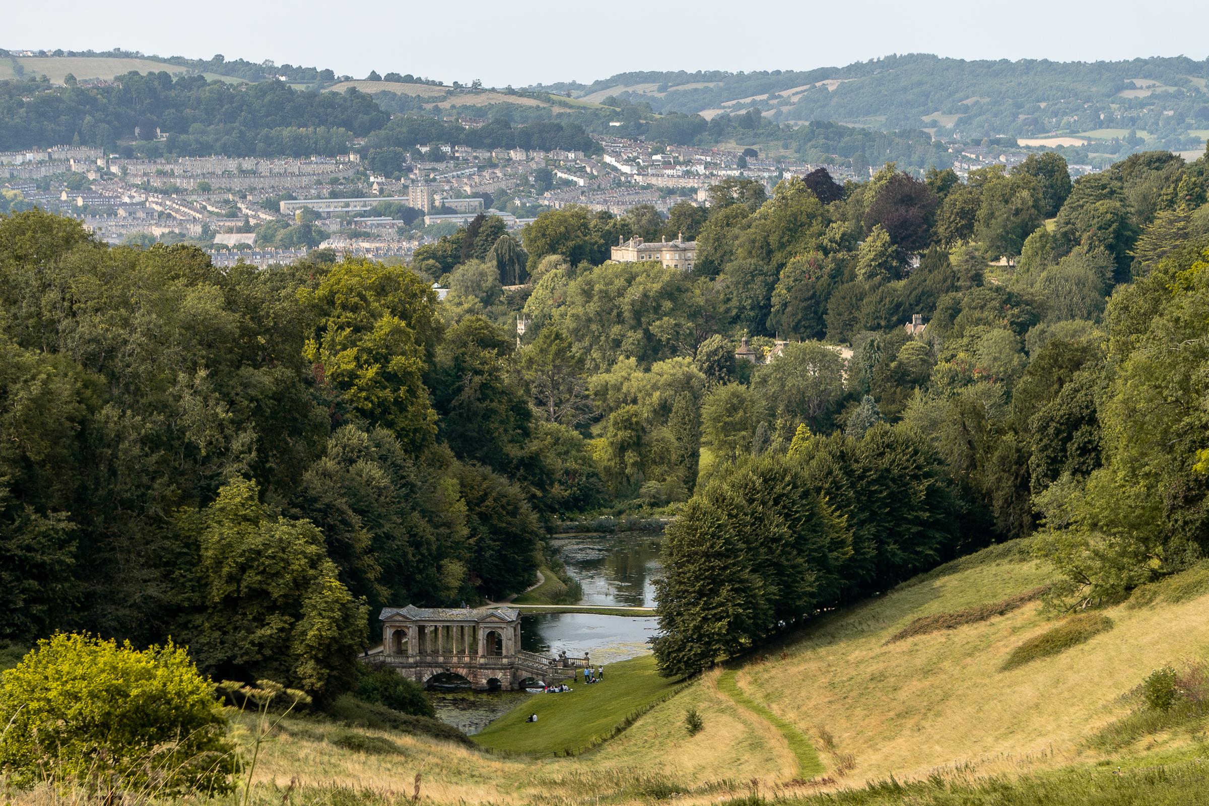 A view of Bath from Prior Park with a lake and Palladian Bridge in the foreground