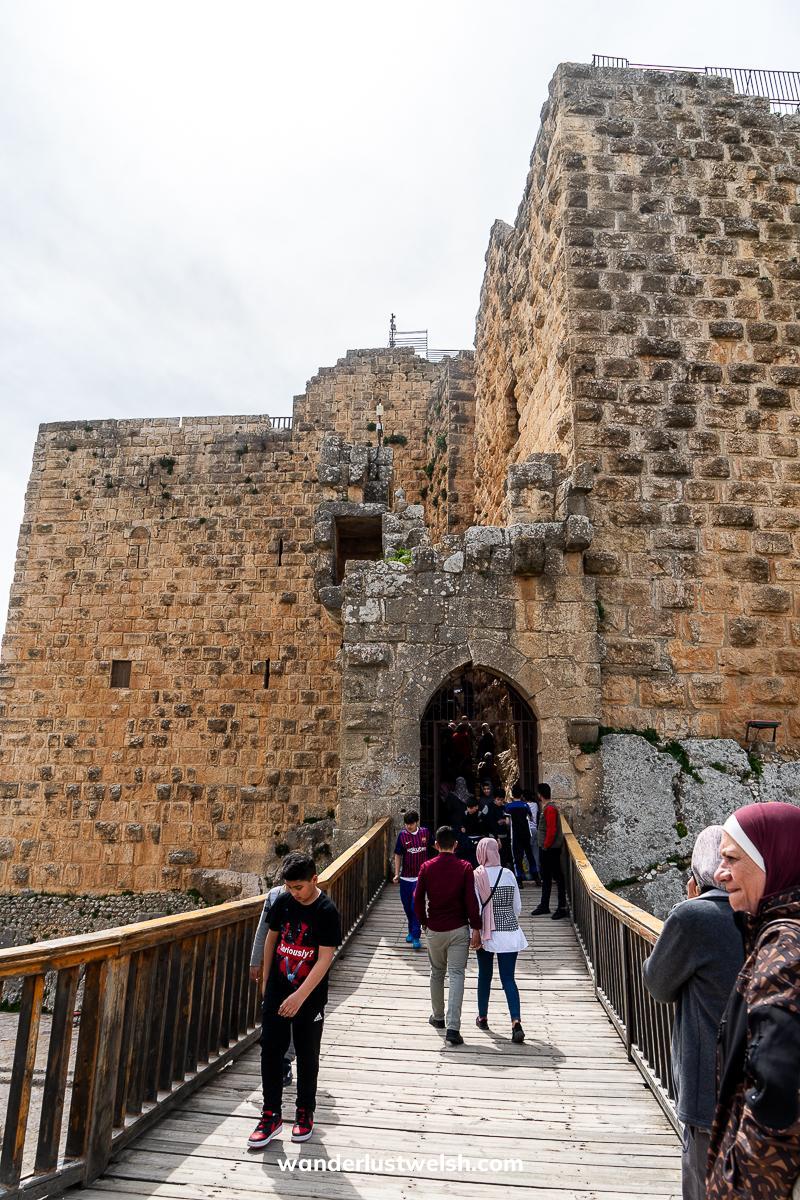 A wooden bridge leading to a large stone castle