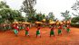 Gitega Drum Sanctuary - Men walking with red, green, and white outfits and large drums on their heads