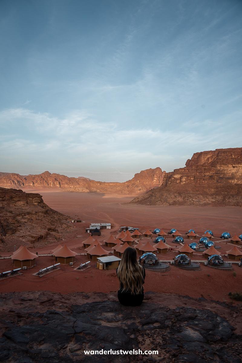 A woman looking out over a resort of glass domes in the Wadi Rum desert