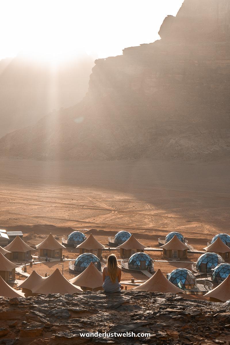 A woman sitting with a view of a desert resort that looks like a martian colony