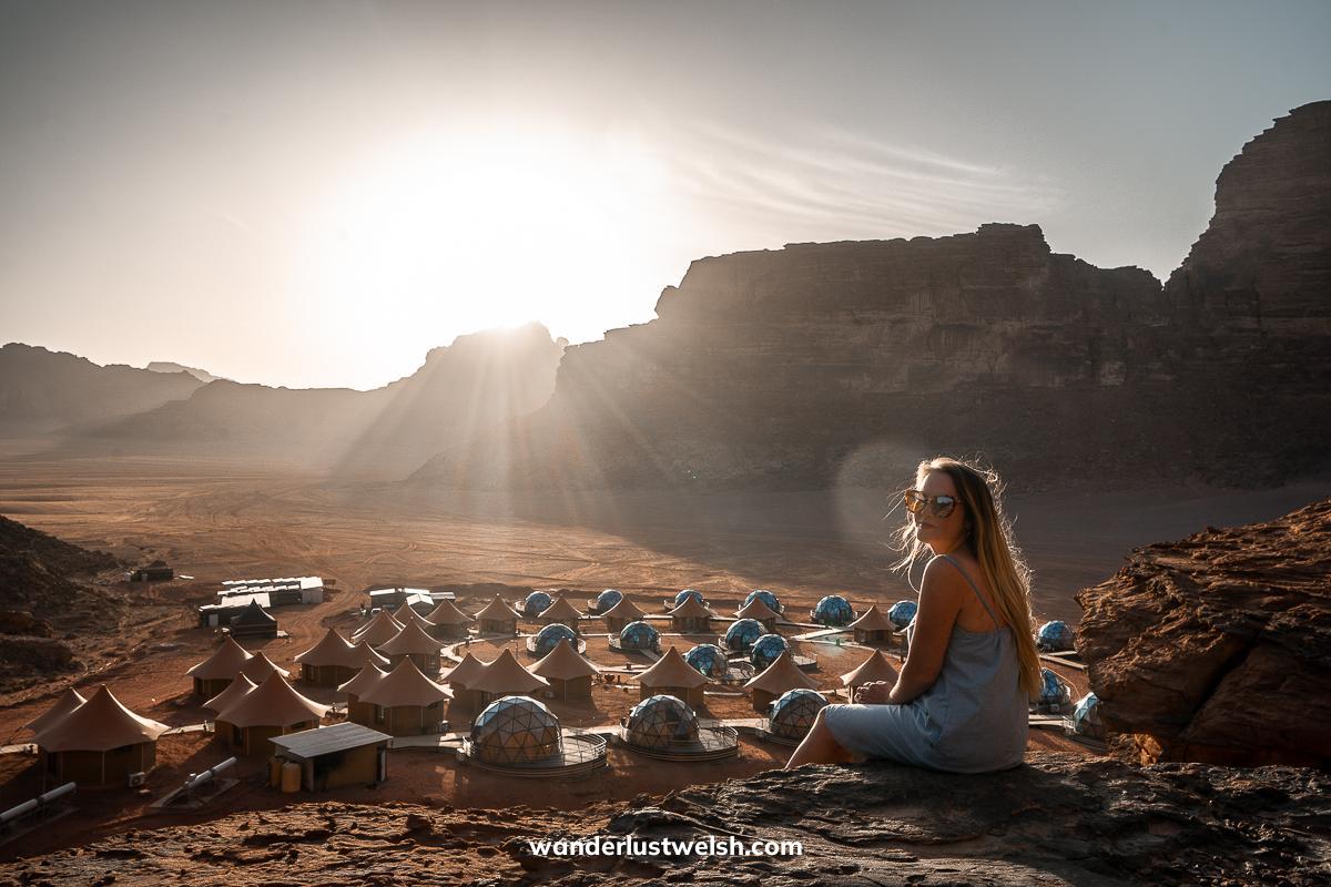 Resort resembling a Martian colony with a woman sitting on a rocky cliff