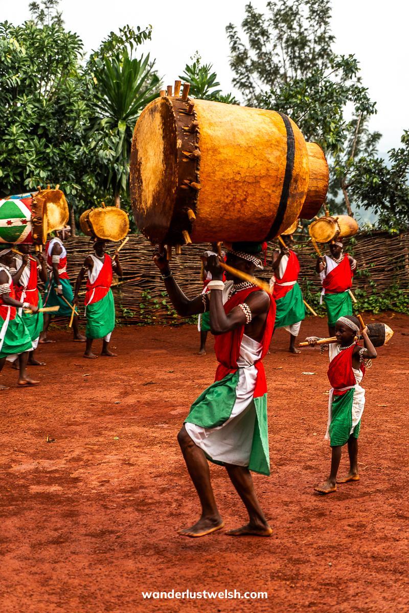Drummers in red, green, and white outfits carrying huge drums on their heads