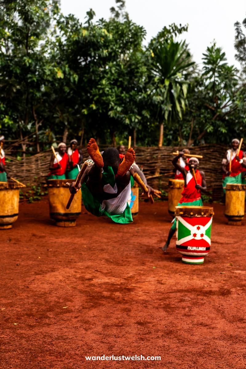 A man in tribal Burundi outfit jumping very high with his feet above his head
