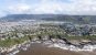 Aerial shot of the Hermanus coastline - muddy sea crashing against the coast with hundreds of small houses behind