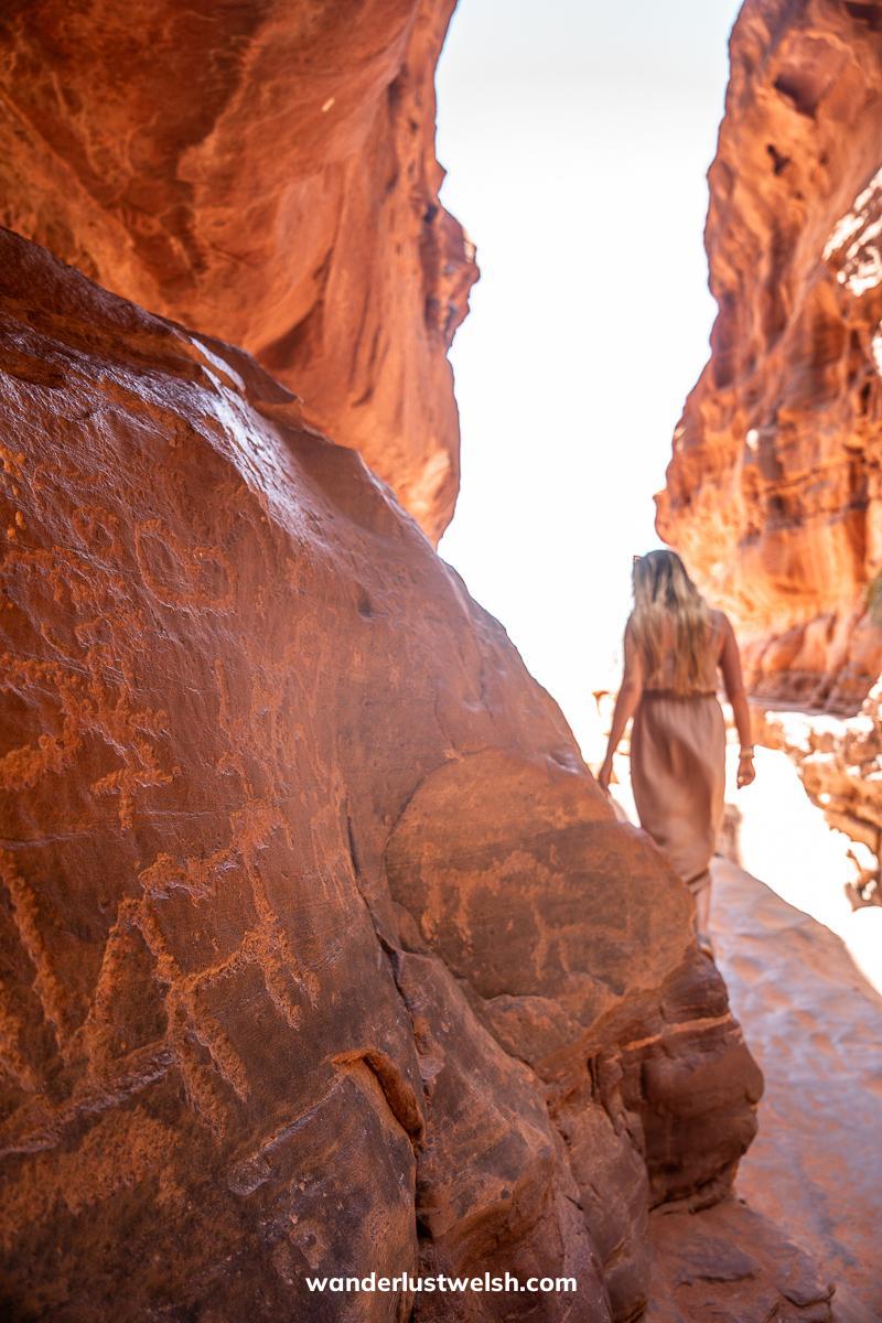 Rock carving petroglyphs in Wadi Rum with a woman walking in the background