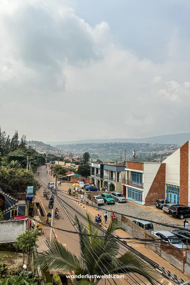 A view of a street in Kigali with houses, cars, and palm trees