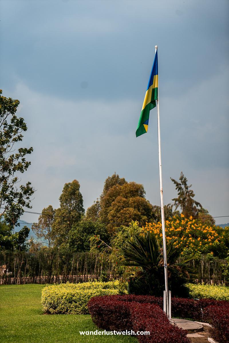 A Rwandan flag at the top of a flagpole in a manicured garden