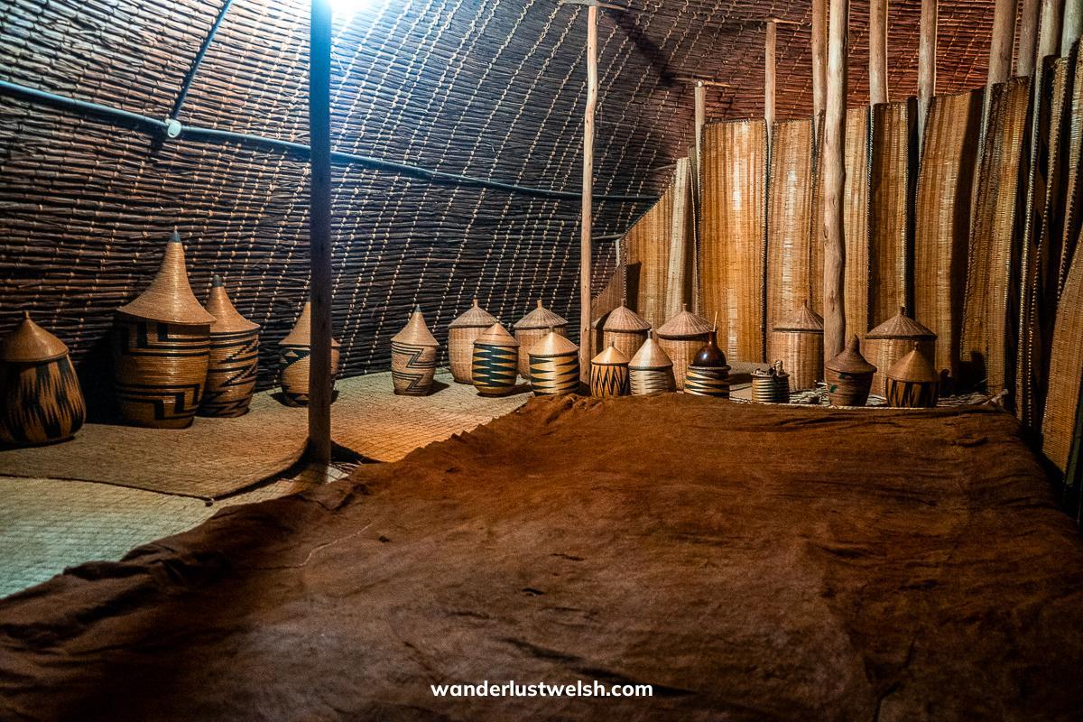 Inside a reconstruction of a Rwandan King's palace - traditional wicker house with large bed and wicker walls, and containers