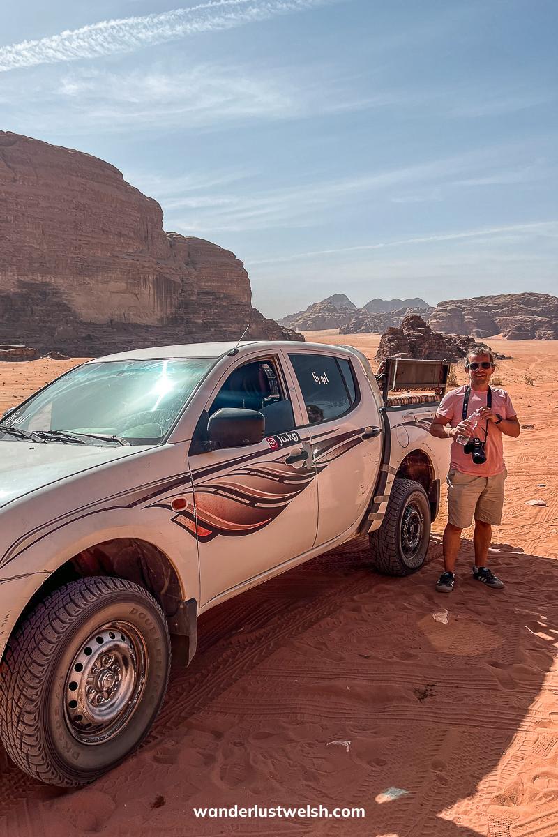 A man with a camera standing next to a pickup truck in the desert