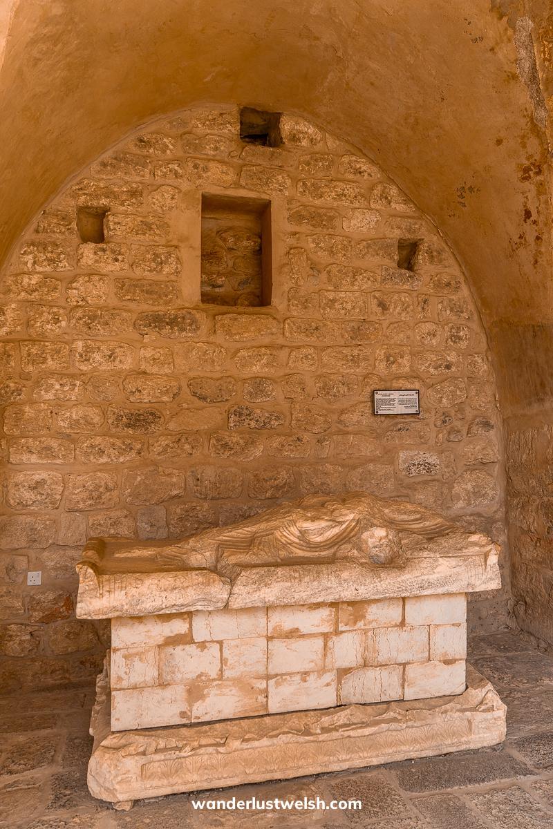 A sandy colored stone mausoleum with tomb