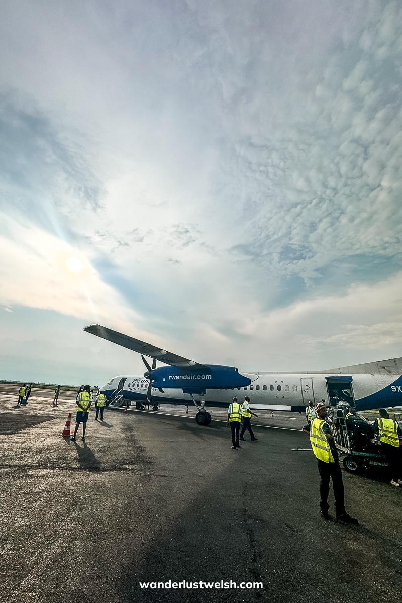 A Rwandair plane on the runway surrounded by airport staff