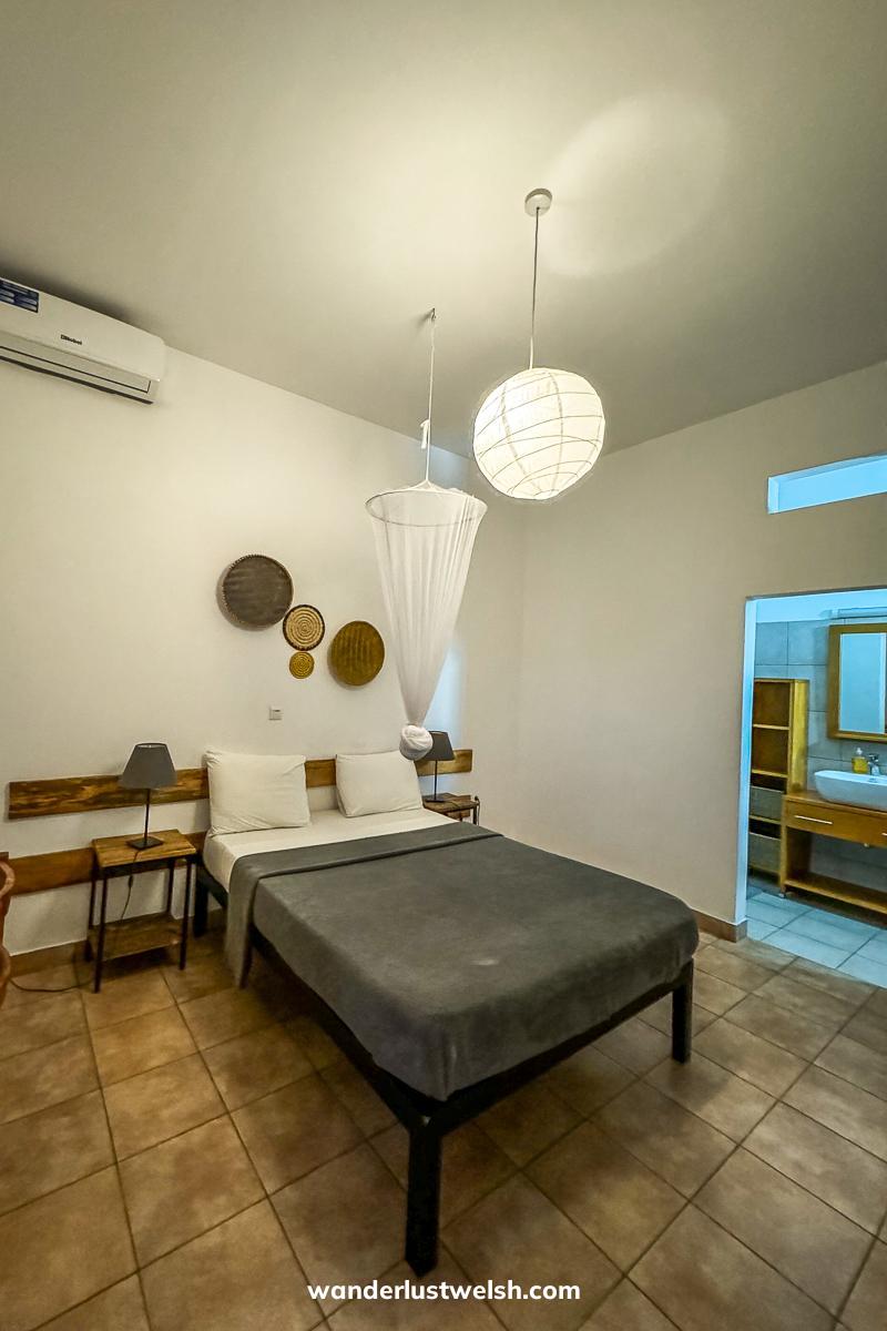A clean hotel room with simple bed, white walls, and wooden decorations