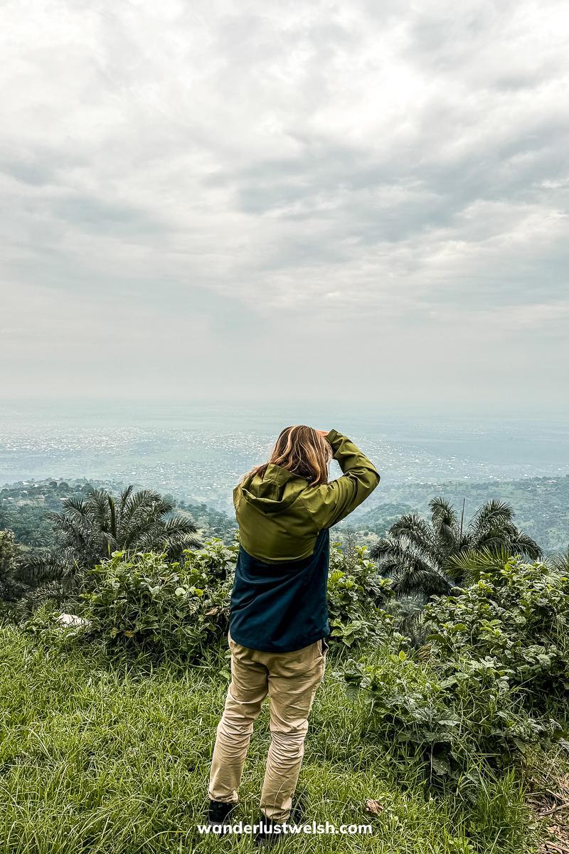 A man in a raincoat taking a photo at a viewpoint in Burundi